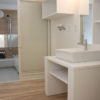造作の洗面化粧台と、奥は浴室。水まわりも白とナチュラルな色合いで統一