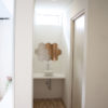 玄関そばにも造作の手洗いスペースは、ハニカム型の鏡がポイントに。右側がトイレ