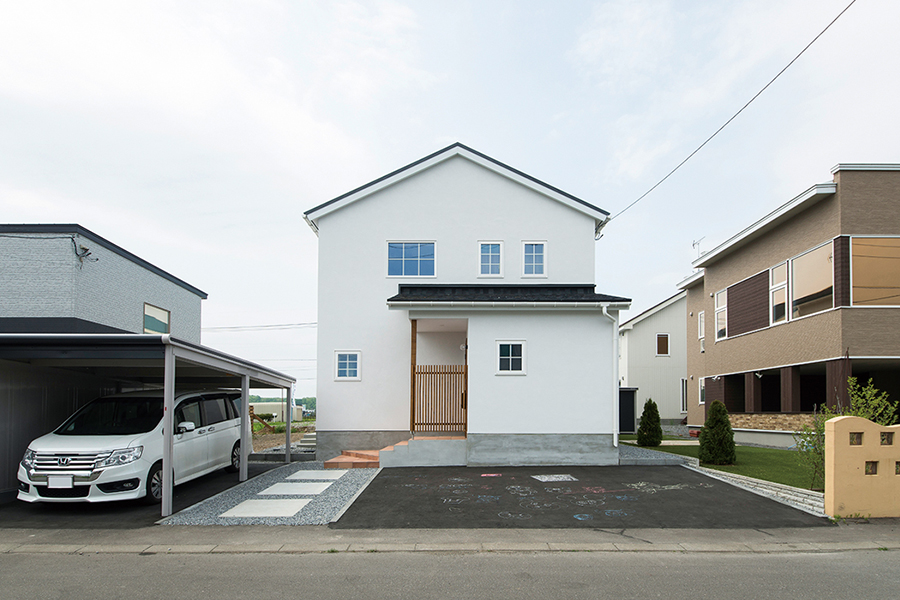 三角屋根のシンプルなフォルムの住まい。駐車スペースも広く確保している