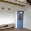 玄関ホールへと続く印象的なブルーのドア。造作のテレビ台の上部には、奥さんセレクトのガラスブロックを埋め込んで、裏側にある洗面スペースへリビングの光を取り入れる
