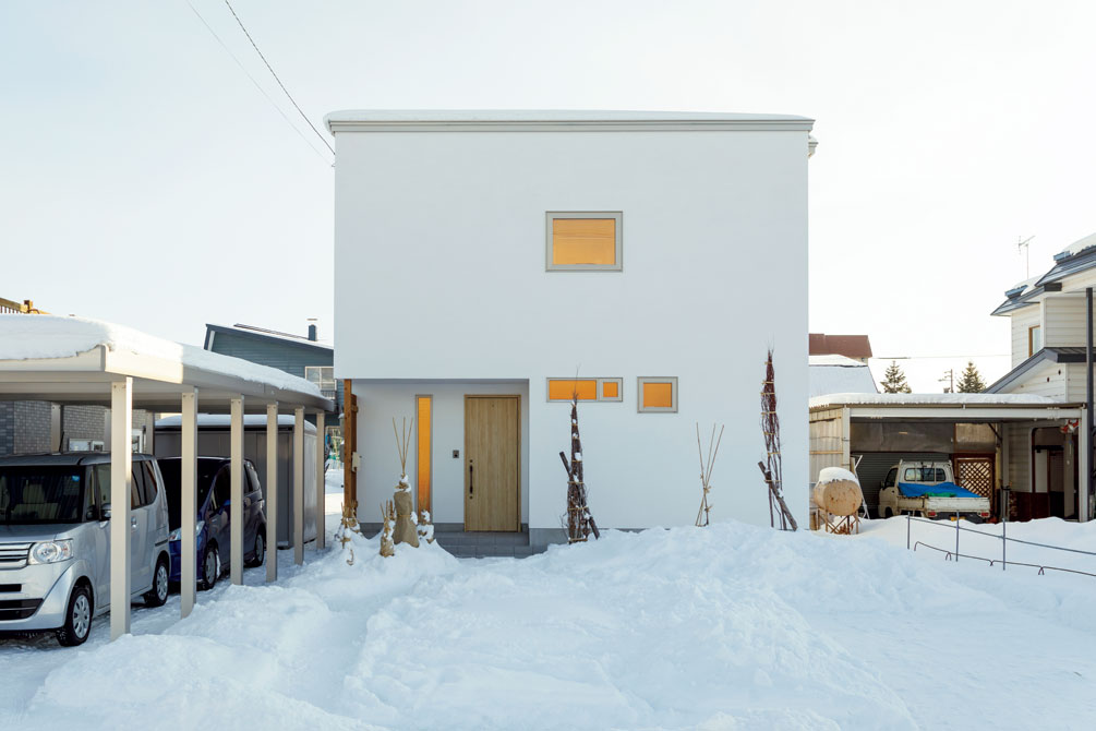 白い塗り壁が美しい外壁。雪のない季節になると、シンプルなこの外観に前庭の樹木が映える