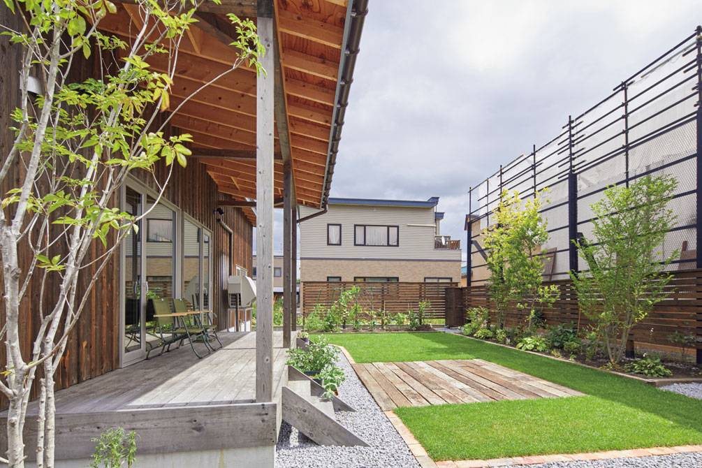 北海道ハウジングの提案で実現した、土間リビング直結のテラスはそのまま、この夏に完成した庭に続く。芝生中央には、バーベキューができるよう枕木を敷いた