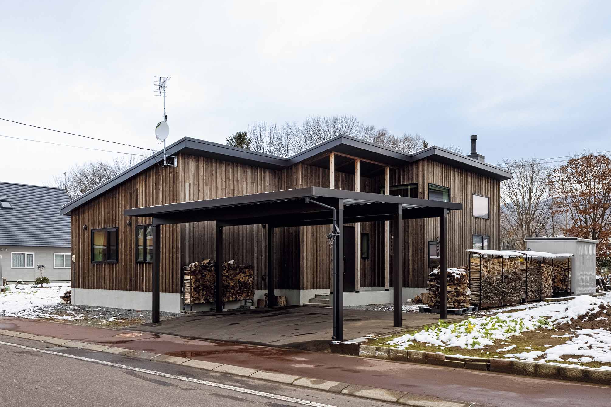 大工の手仕事で仕上げられたカラマツ板張りの外壁が端正な佇まいをつくる外観。屋根付きカーポートで雪対策も万全